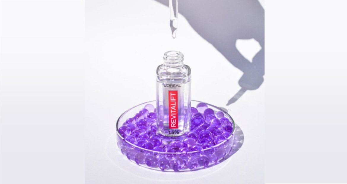 Sérum facial Revitalift Hialurônico com conta gotas em um recipiente com bolas azul em um fundo branco.